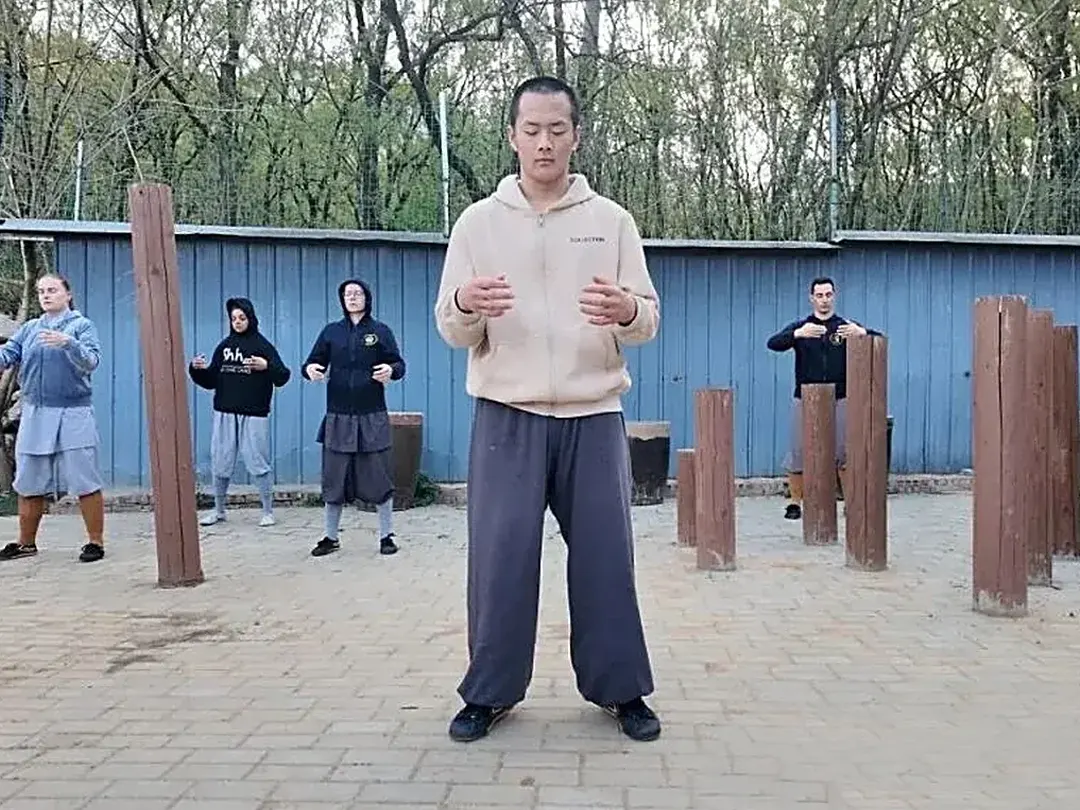 Coach explaining kung fu basics to international students at the training ground