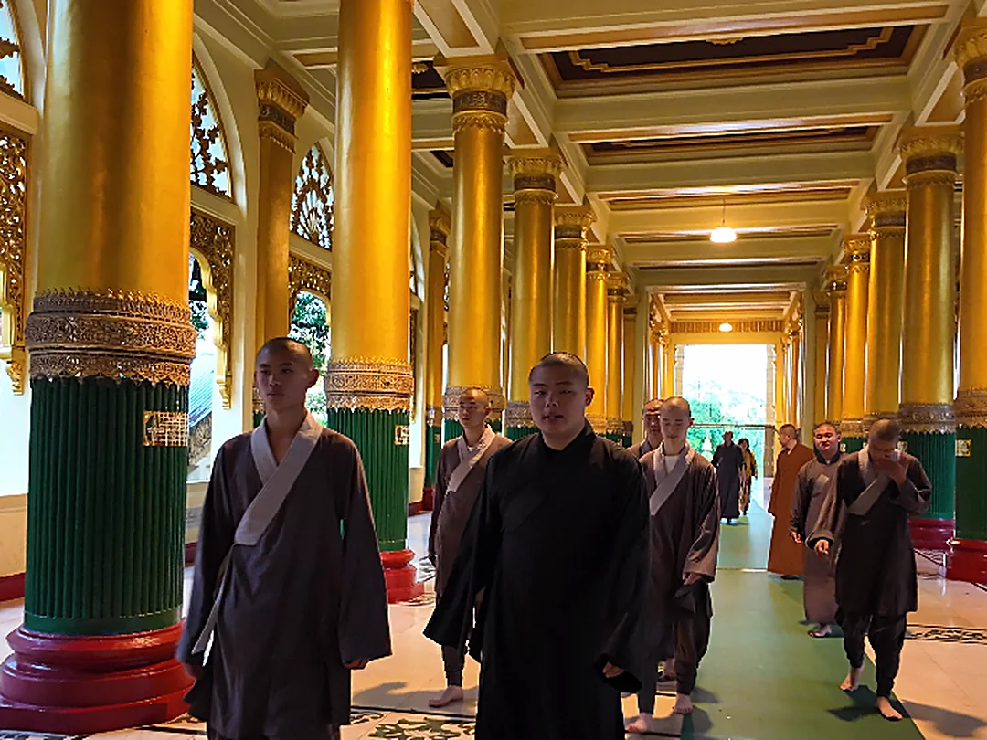 Shaolin Zhongwu monks walking in formation through a golden corridor in Myanmar