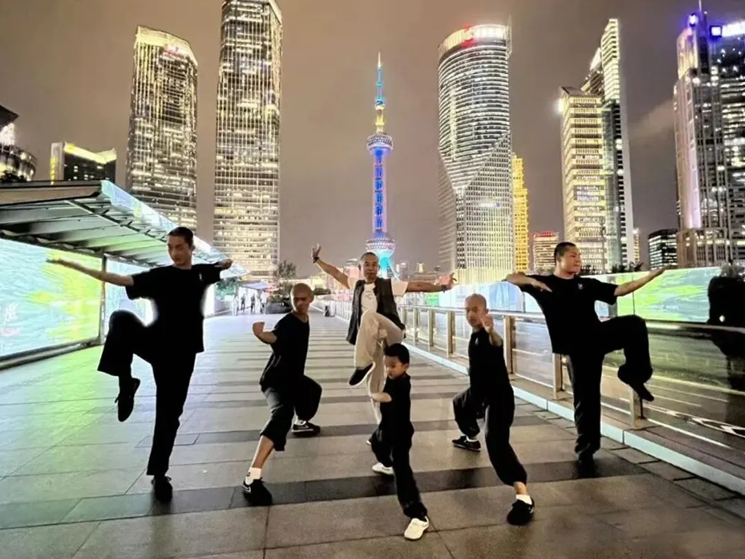 Young students posing kung fu stances in front of the Shanghai skyline at night