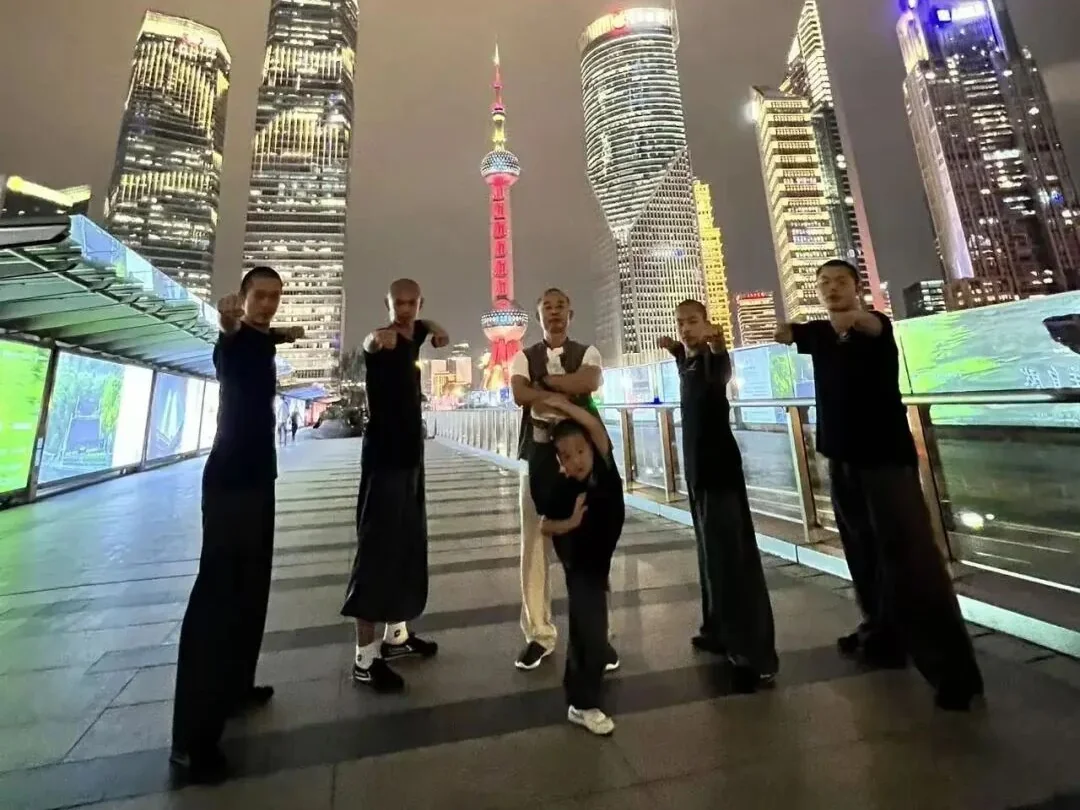 Young Shaolin students throwing punches in front of the Huangpu River night view