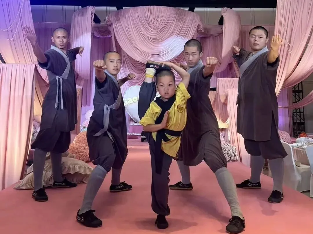 Young Shaolin student performing the skyward kick on the stage in Shanghai