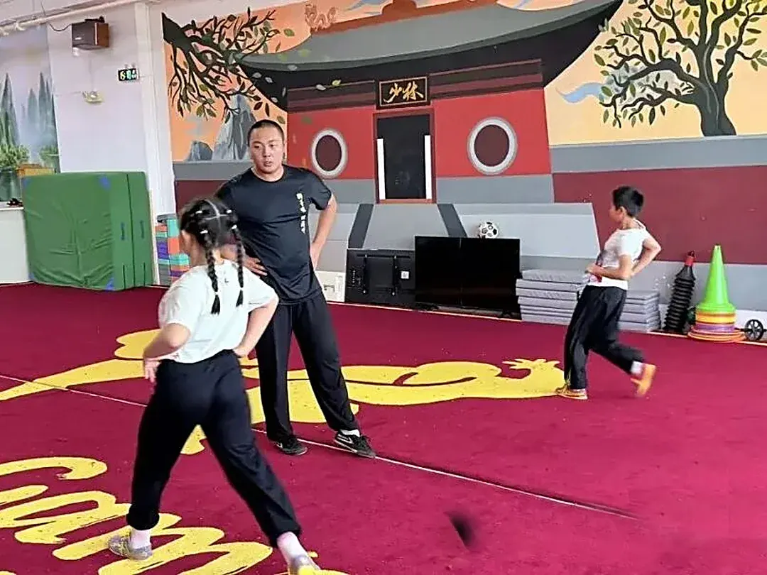 Students practicing stances in front of the Shaolin gate mural in Singapore