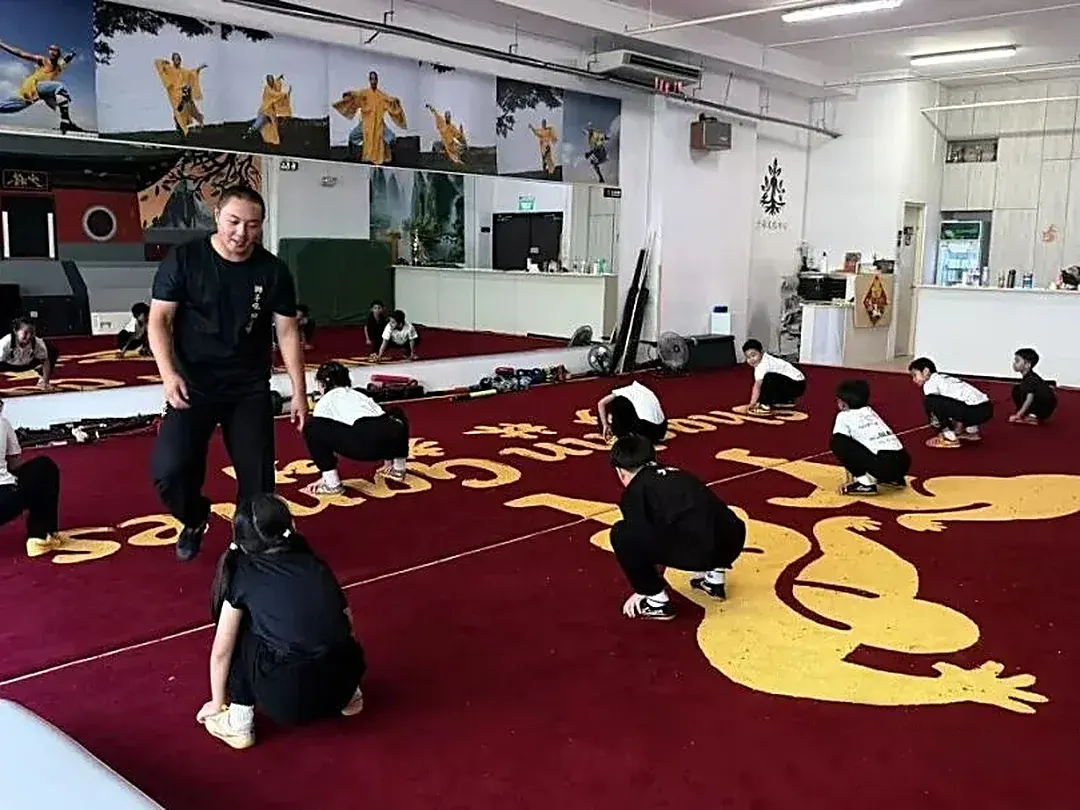 Students practicing crouching stances on the training mats in Singapore