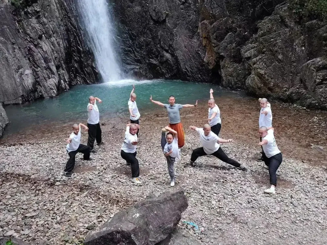 Shaolin Zhongwu students posing kung fu forms at a waterfall in the Nanxi River area
